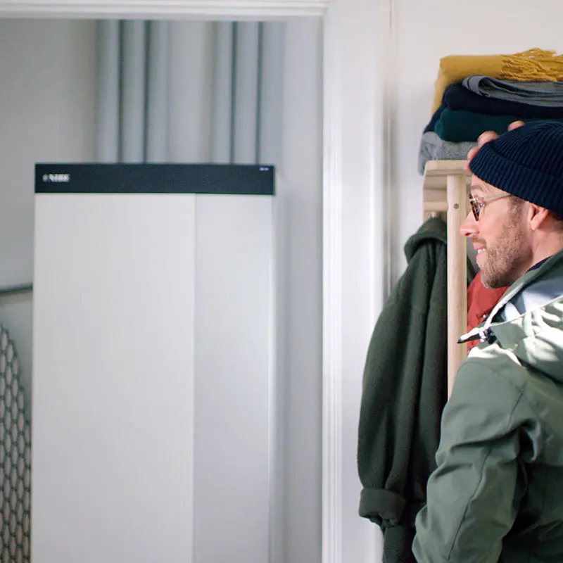 Man in hallway besides ground source heatpump