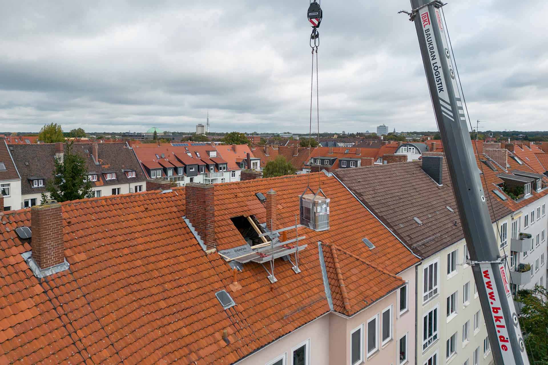 Wärmepumpe wird durch Kran über das Dach gehoben