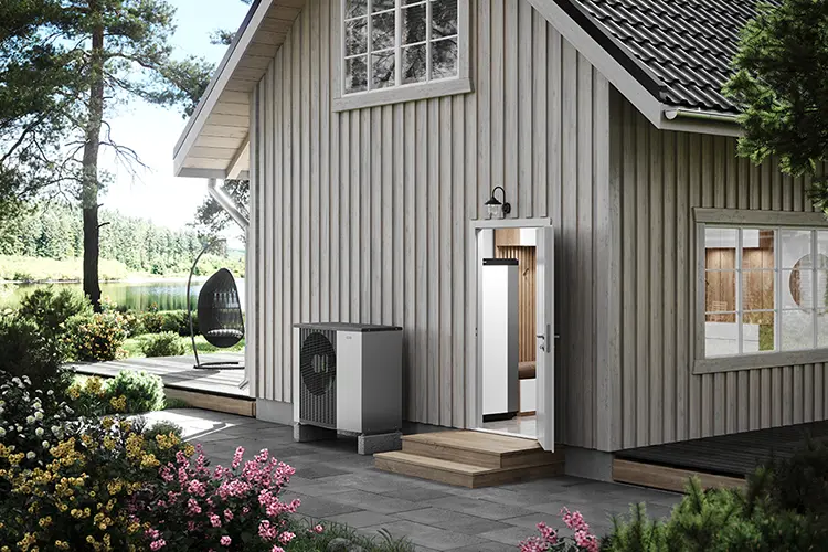 NIBE Luft/Wasser-Wärmepumpe vor einem Holzhaus