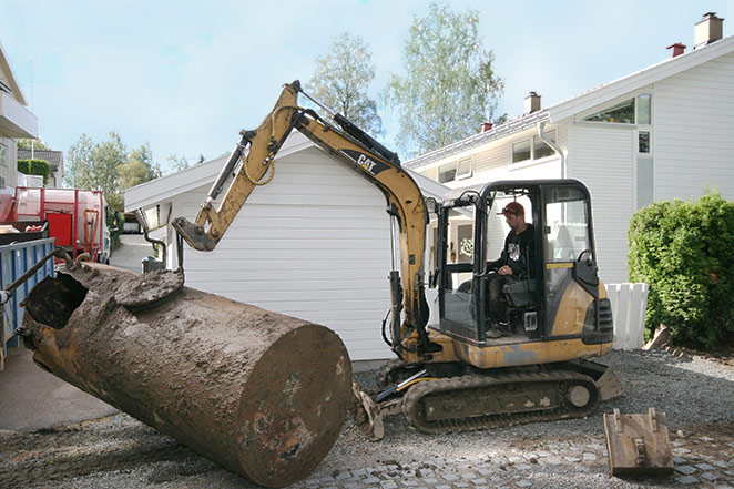 En gravemaskin som graver opp en oljetank fra bakken