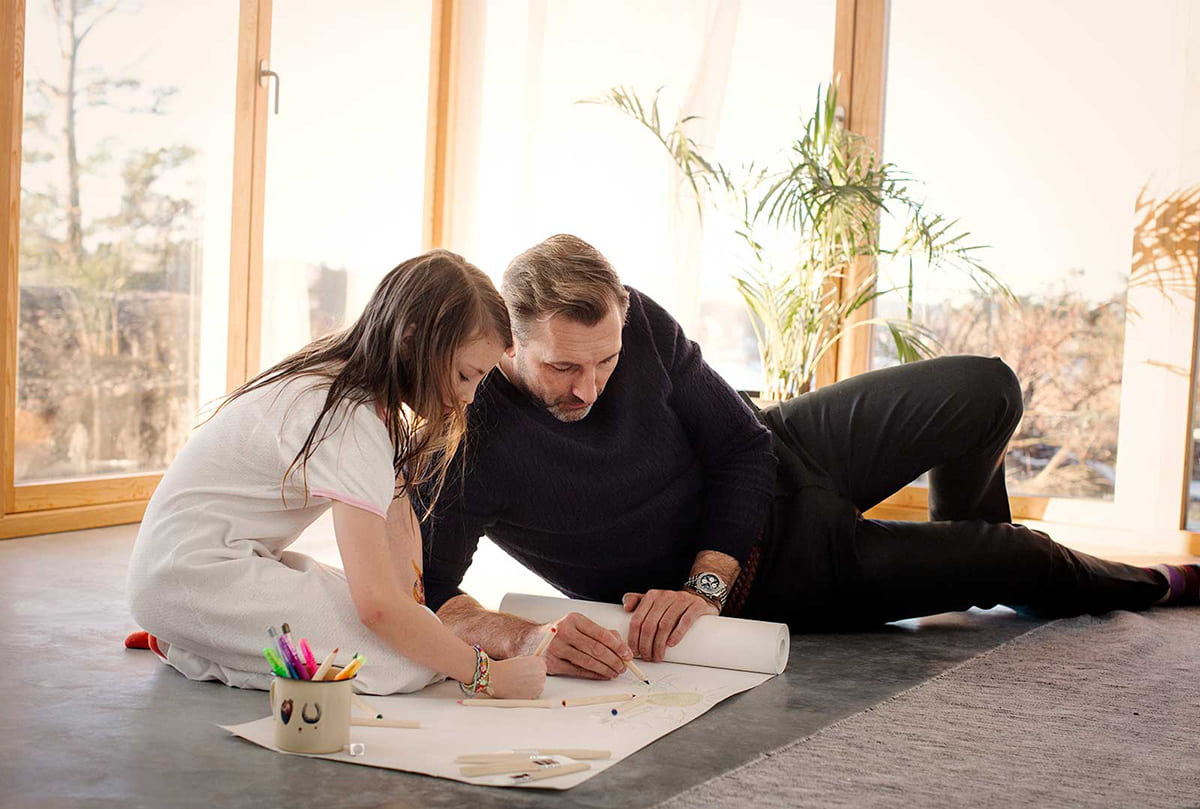 En far og datter som tegner sammen på gulvet