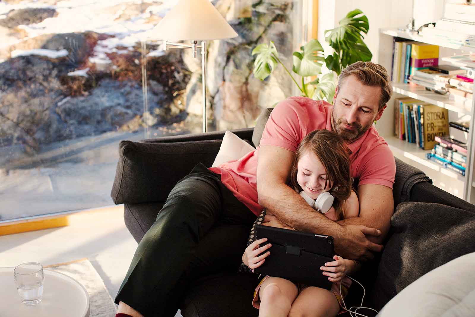 Tata przytula dziecko na kanapie w domu ogrzewanym pompą ciepła domu.