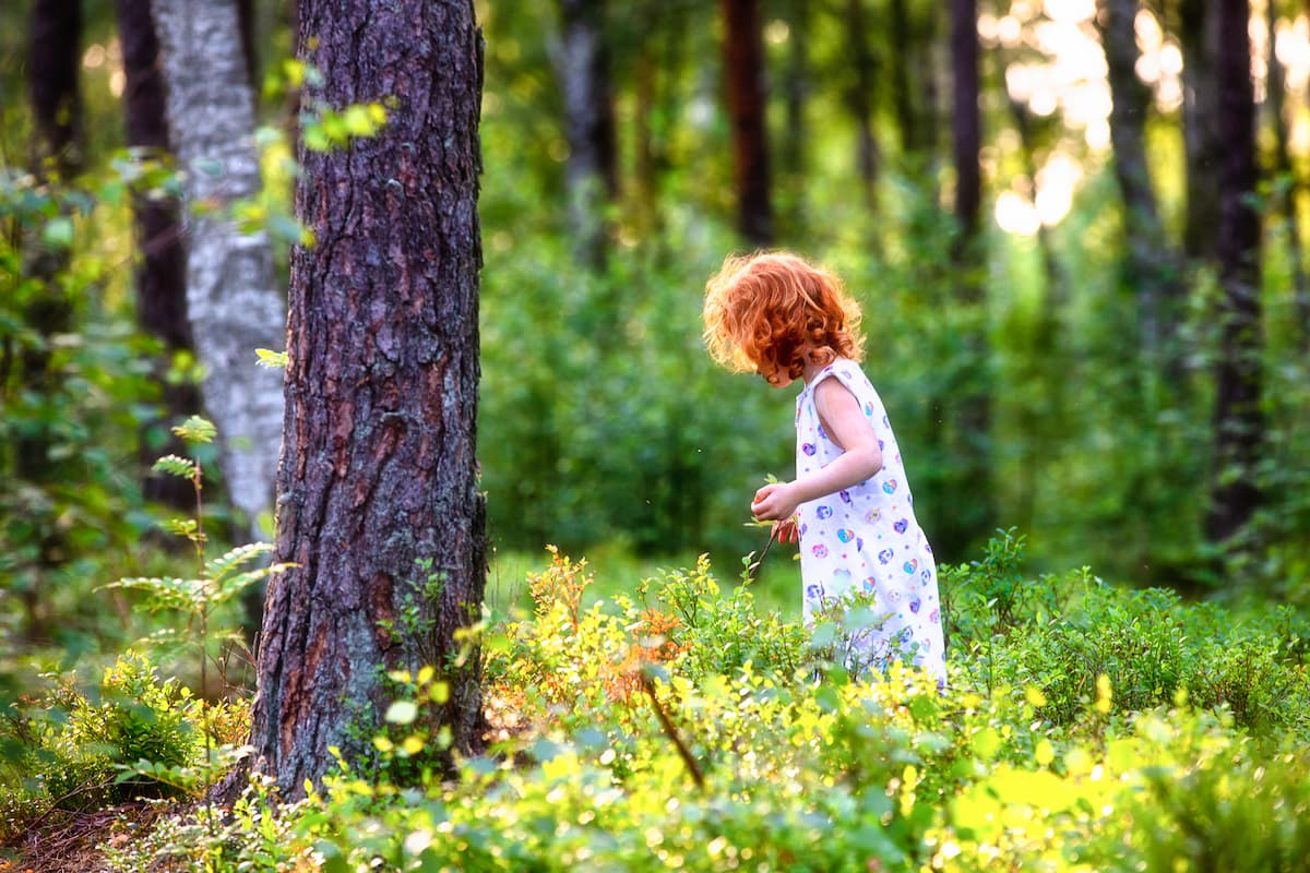 Dziewczynka bawiąca się w lesie.